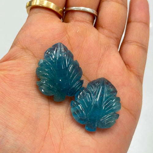 Matched pair of hand-carved aquamarine leaves, 62.59 carats total, held in an open palm for scale